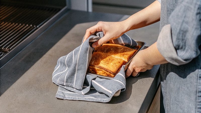 Un cuenco con masa de pan cubierta por un paño de cocina estampado.