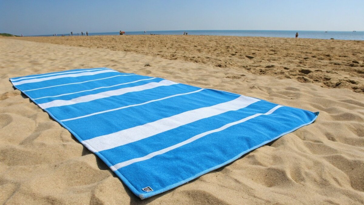 A colorful beach towel laid out on the sand