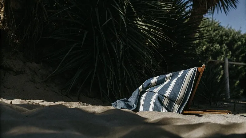 Una persona se cubre con una toalla de playa grande mientras pasea por la playa.